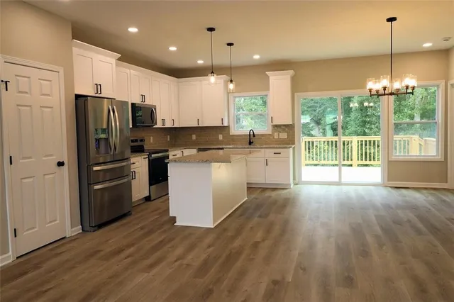 a kitchen with kitchen island wooden floors appliances and cabinets
