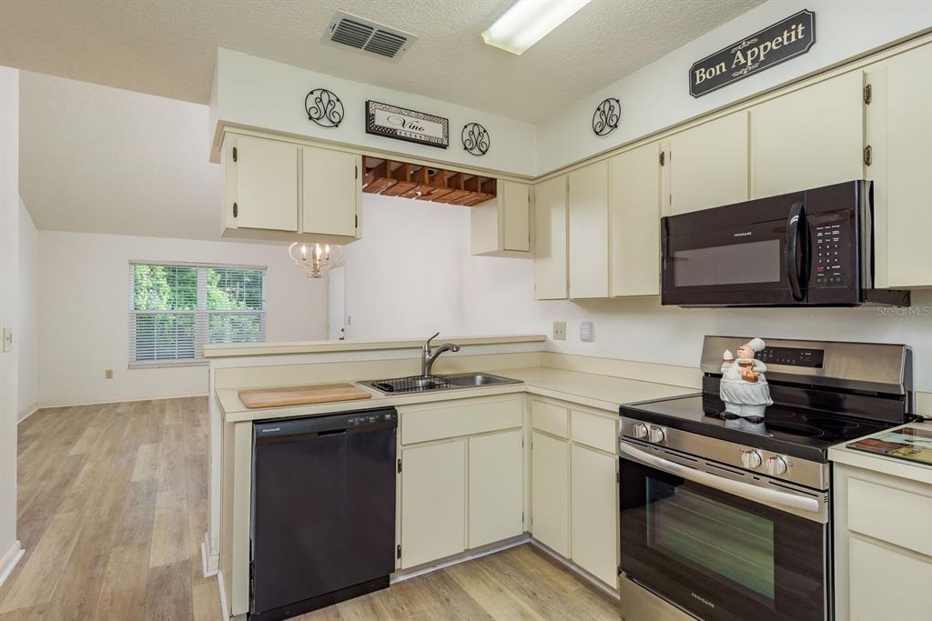 6410 Spring Flower Drive, Unit 26 New Port Richey, FL 34653 - Photo 15 of 38 a kitchen with stainless steel appliances granite countertop a sink stove top oven and microwave