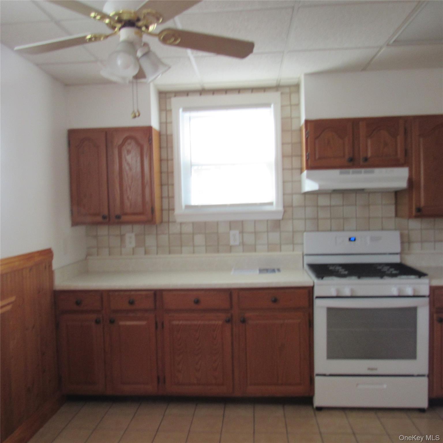35 Taylor Avenue, Unit 2 Poughkeepsie, NY 12601 - Photo 6 of 19 Kitchen with white range with gas stovetop, brown cabinetry, light countertops, ceiling fan, and exhaust hood
