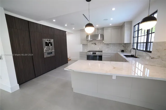 a large kitchen with stainless steel appliances a large counter top a refrigerator and a sink