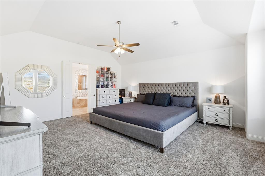 6508 Cooper Creek Road Flower Mound, TX 76226 - Photo 17 of 39 a spacious bedroom with a bed and a chandelier