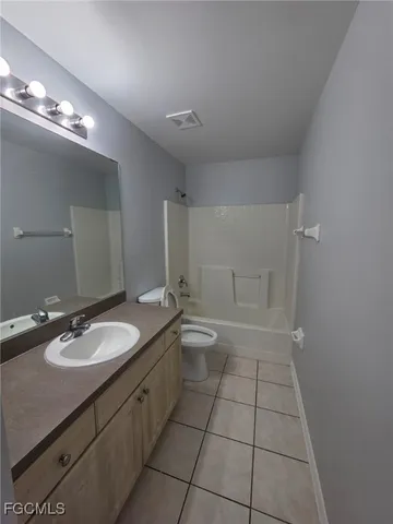 a bathroom with a granite countertop sink a toilet a mirror and a shower