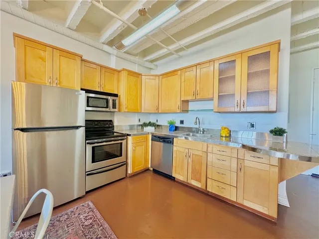 a kitchen with stainless steel appliances granite countertop a stove a sink dishwasher a refrigerator and cabinets with wooden floor