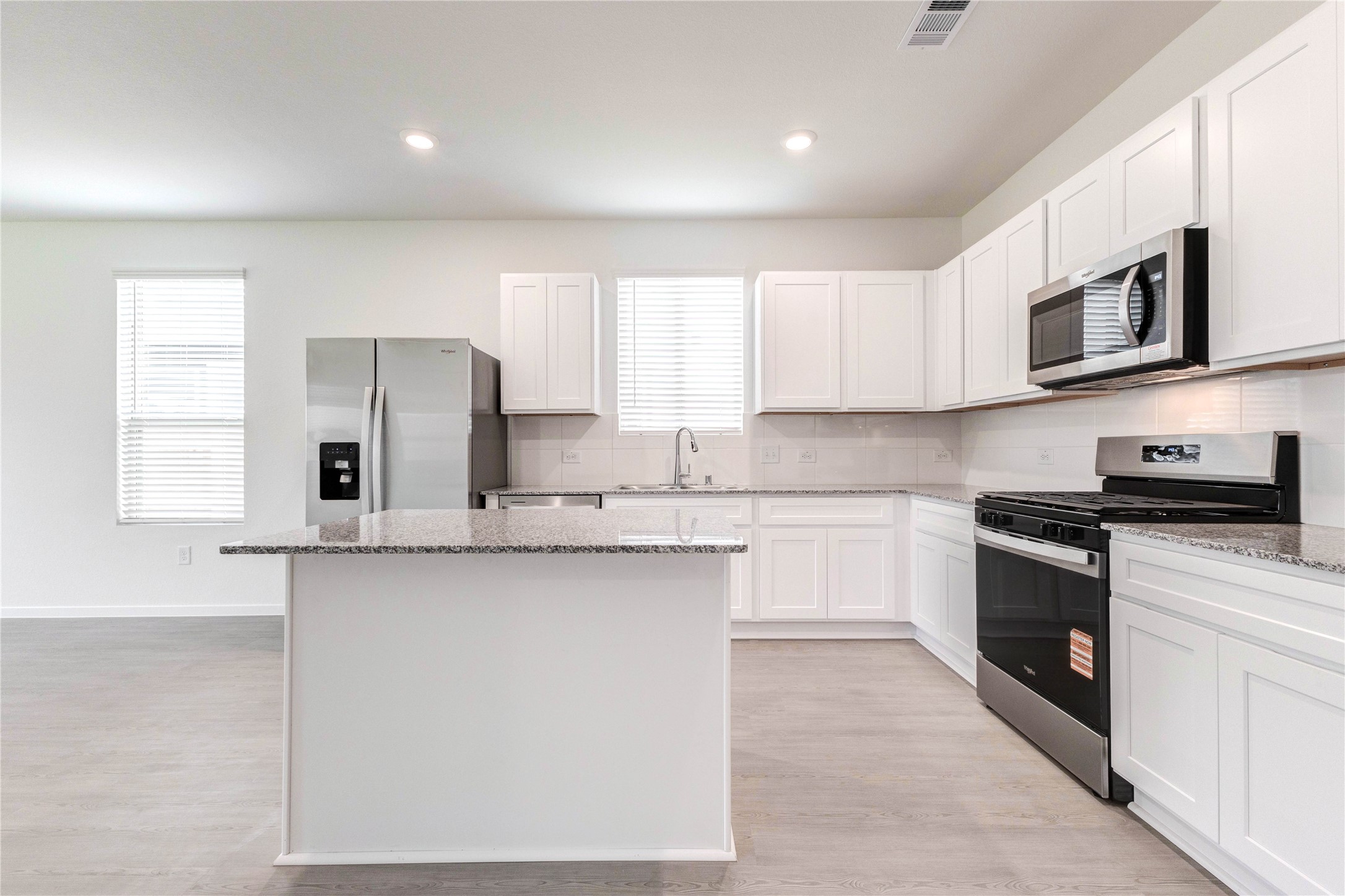 15011 Rustic Moon Road Conroe, TX 77302 - Photo 7 of 26 a kitchen with stainless steel appliances granite countertop a sink and a stove top oven with white cabinets