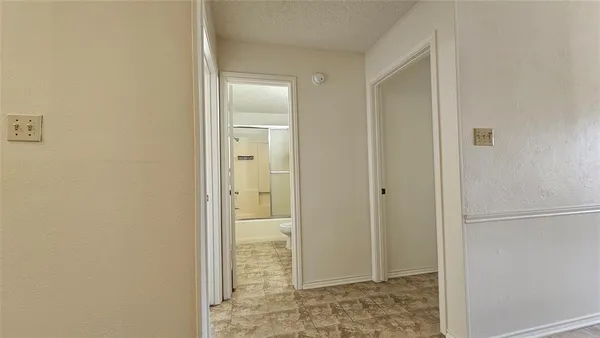 an empty room with a chandelier fan and windows