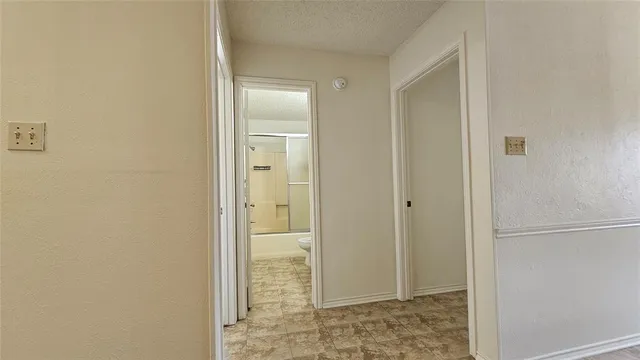 an empty room with a chandelier fan and windows