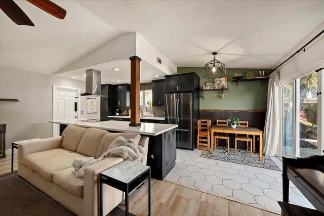 a living room with furniture a chandelier and kitchen view
