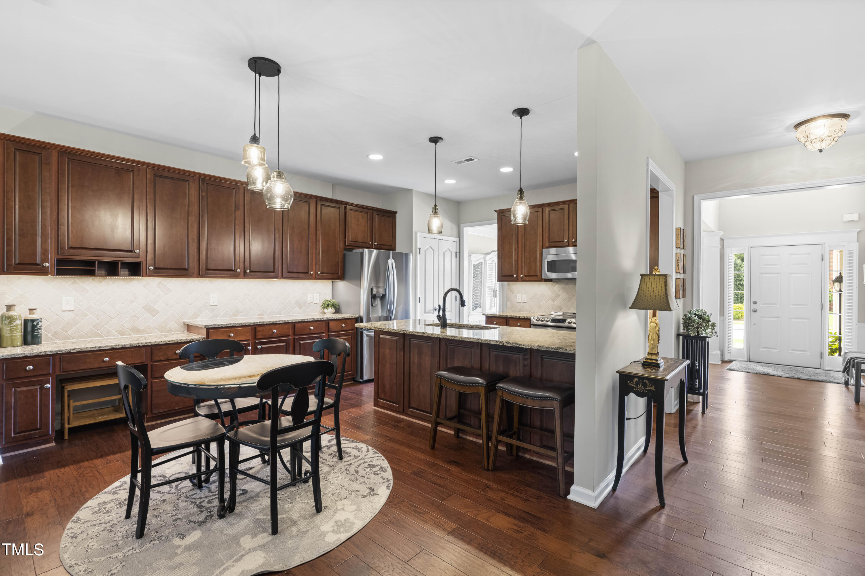 4604 Manassa Pope Lane Raleigh, NC 27612 - Photo 7 of 43 a kitchen with stainless steel appliances kitchen island granite countertop a table chairs sink and cabinets