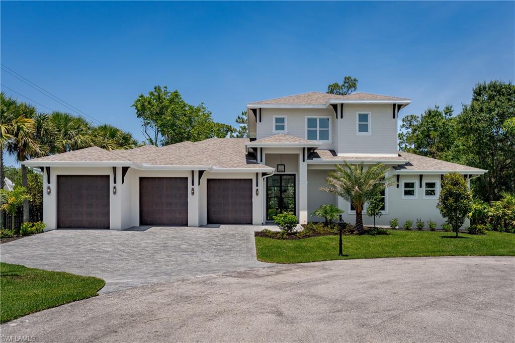2854 Coach House Way Naples, FL 34105 - Photo 1 of 50 View of front facade featuring decorative driveway, an attached garage, a front lawn, stucco siding, and roof with shingles