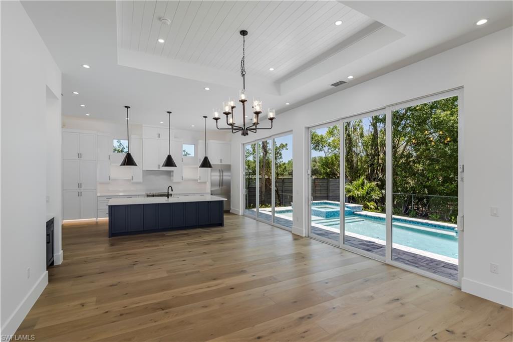 2854 Coach House Way Naples, FL 34105 - Photo 11 of 50 Kitchen with a raised ceiling, a sink, white cabinetry, recessed lighting, and light countertops