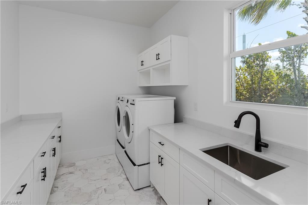 2854 Coach House Way Naples, FL 34105 - Photo 12 of 50 Laundry room featuring washing machine and clothes dryer, cabinet space, light marble finish flooring, and baseboards