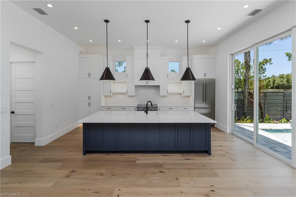 2854 Coach House Way Naples, FL 34105 - Photo 14 of 50 Kitchen featuring high end fridge, white cabinetry, baseboards, tasteful backsplash, and recessed lighting