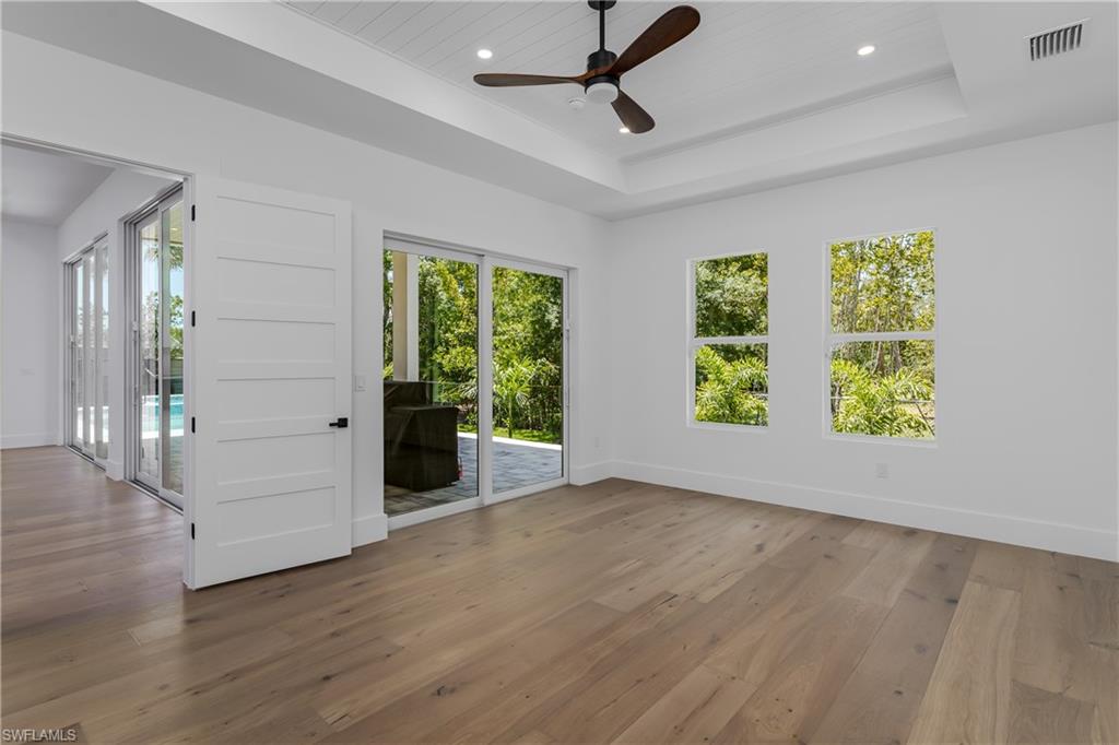 2854 Coach House Way Naples, FL 34105 - Photo 17 of 50 Spare room with healthy amount of natural light, ceiling fan, wood-type flooring, a tray ceiling, and recessed lighting