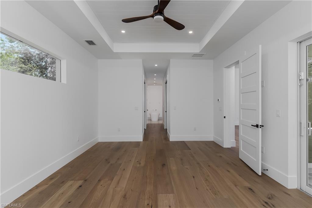2854 Coach House Way Naples, FL 34105 - Photo 18 of 50 Unfurnished bedroom featuring a tray ceiling, hardwood / wood-style flooring, recessed lighting, baseboards, and ceiling fan