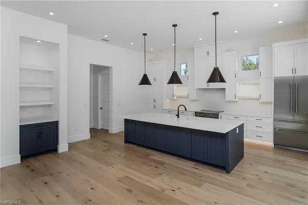 a kitchen with stainless steel appliances a sink a stove a refrigerator and island with wooden floor