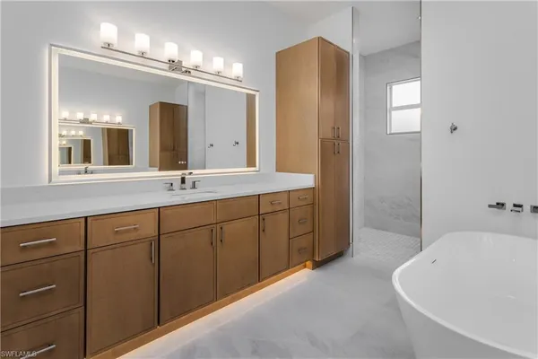 a spacious bathroom with a double vanity sink a large mirror and a bathtub