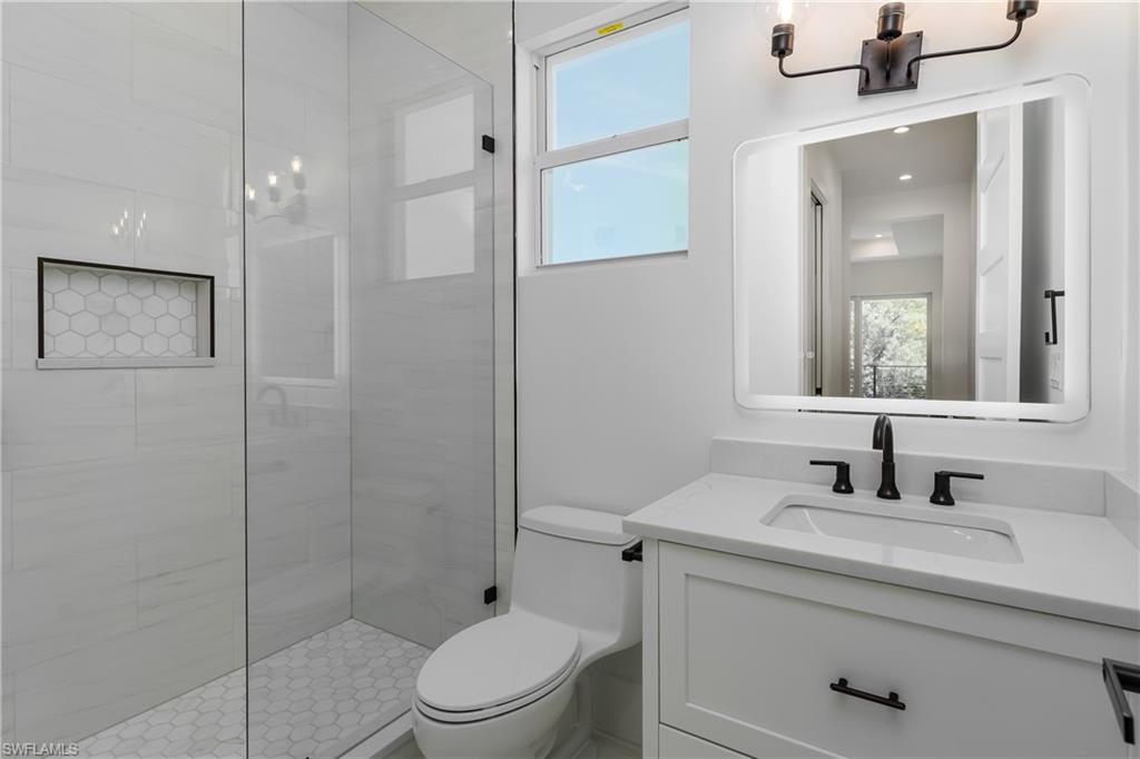 2854 Coach House Way Naples, FL 34105 - Photo 31 of 45 Bathroom with toilet, vanity, healthy amount of natural light, and tiled shower