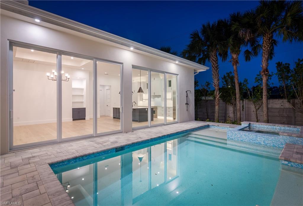 2854 Coach House Way Naples, FL 34105 - Photo 49 of 50 Pool at night featuring a patio area, a fenced backyard, and a pool with connected hot tub