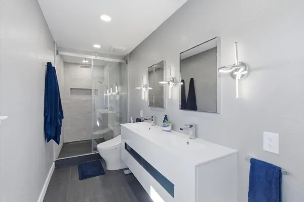 a bathroom with a granite countertop sink a mirror and shower