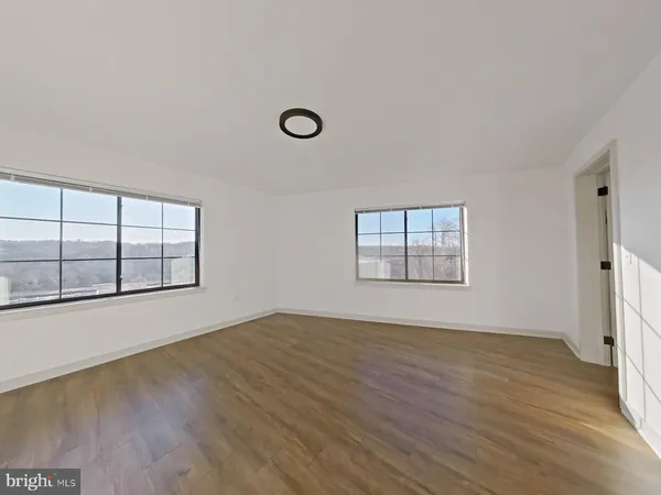 an empty room with wooden floor and windows