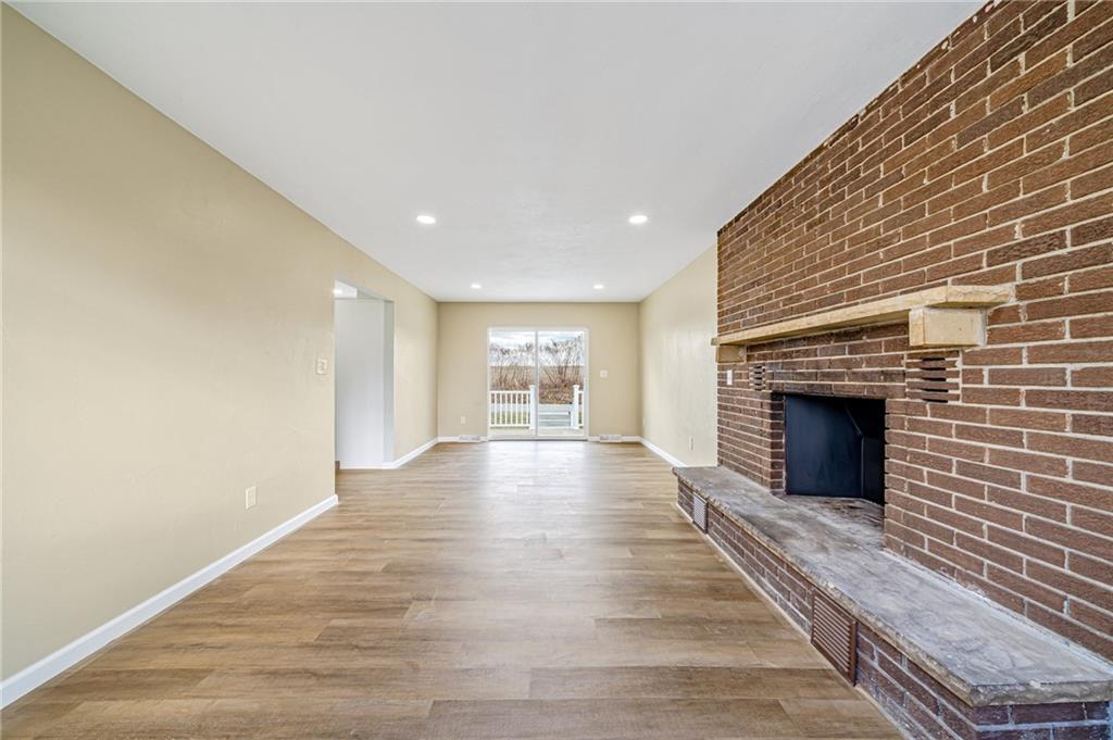 608 Fitz Henry Road Smithton, PA 15479 - Photo 16 of 40 an empty room with wooden floor fireplace and windows