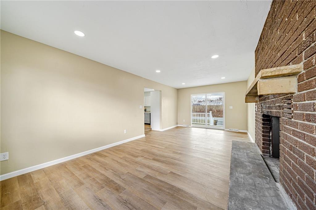 608 Fitz Henry Road Smithton, PA 15479 - Photo 17 of 40 an empty room with wooden floor and fireplace