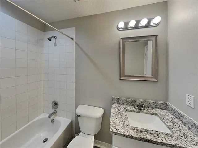 a bathroom with a granite countertop sink a toilet and bathtub