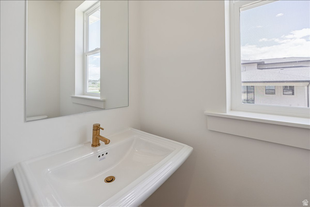 952 Mathilda Drive, Unit 156 Saratoga Springs, UT 84045 - Photo 10 of 25 Pedestal sink with brass-finish faucet and drain, complemented by a large wall-mounted mirror