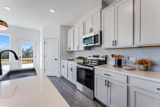 a kitchen with stainless steel appliances kitchen island granite countertop a stove top oven a sink a dining table and chairs with wooden floor