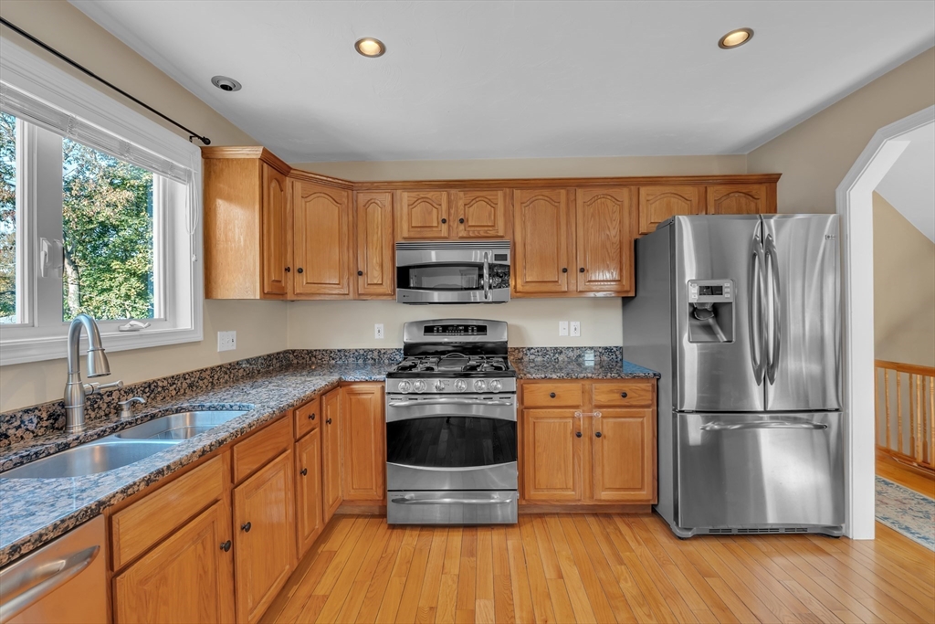133 Derby Street Worcester, MA 01604 - Photo 5 of 42 a kitchen with granite countertop wooden floors stainless steel appliances a sink and a window