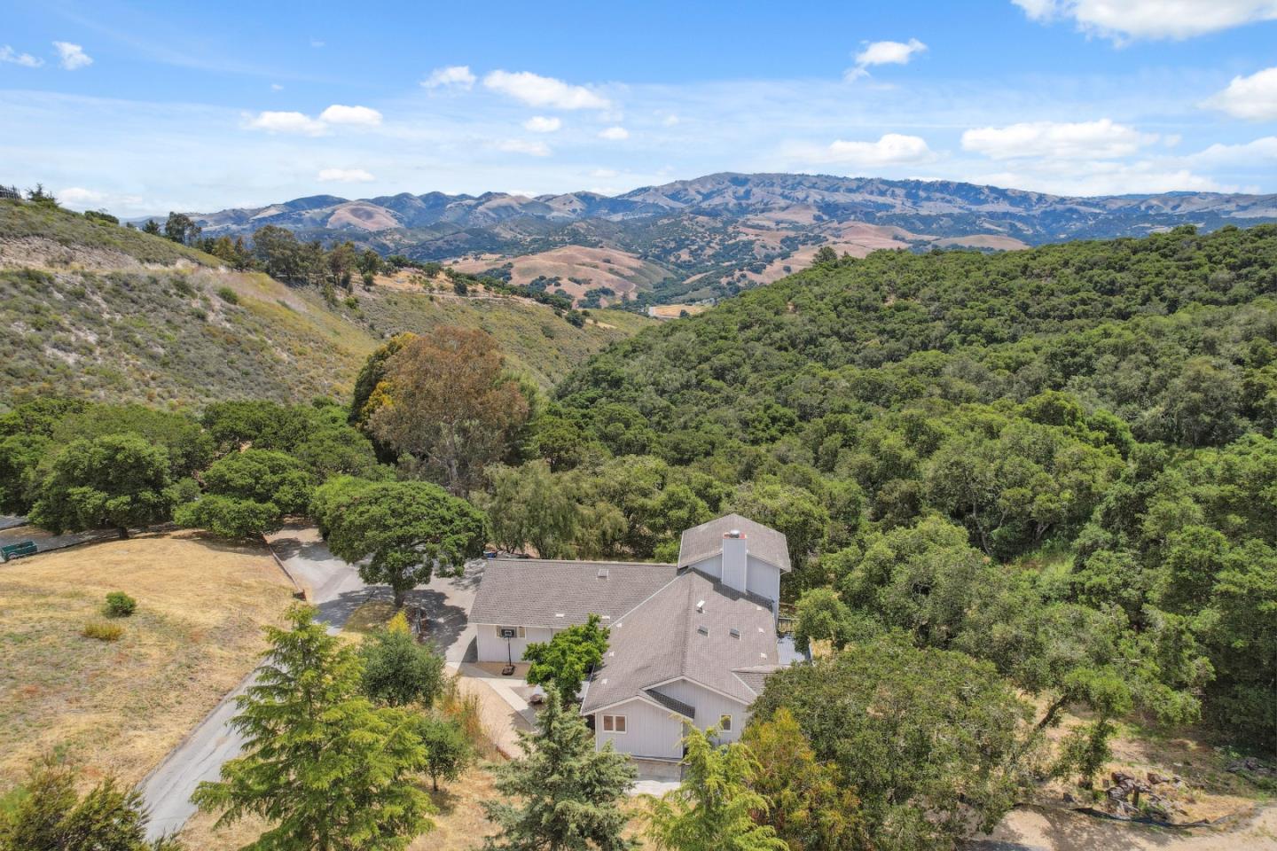 an aerial view of a houses with a yard and mountain view in back