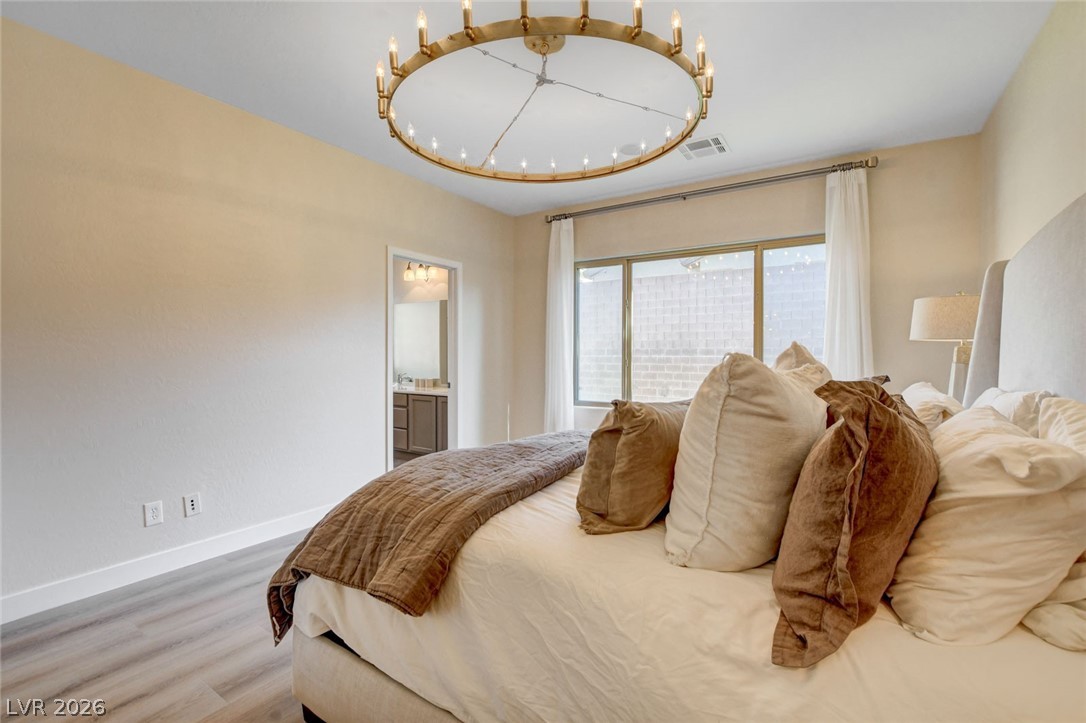 2649 Rue Marquette Avenue Henderson, NV 89044 - Photo 44 of 55 This tranquil bedroom features a striking chandelier and durable flooring, offering a peaceful retreat.