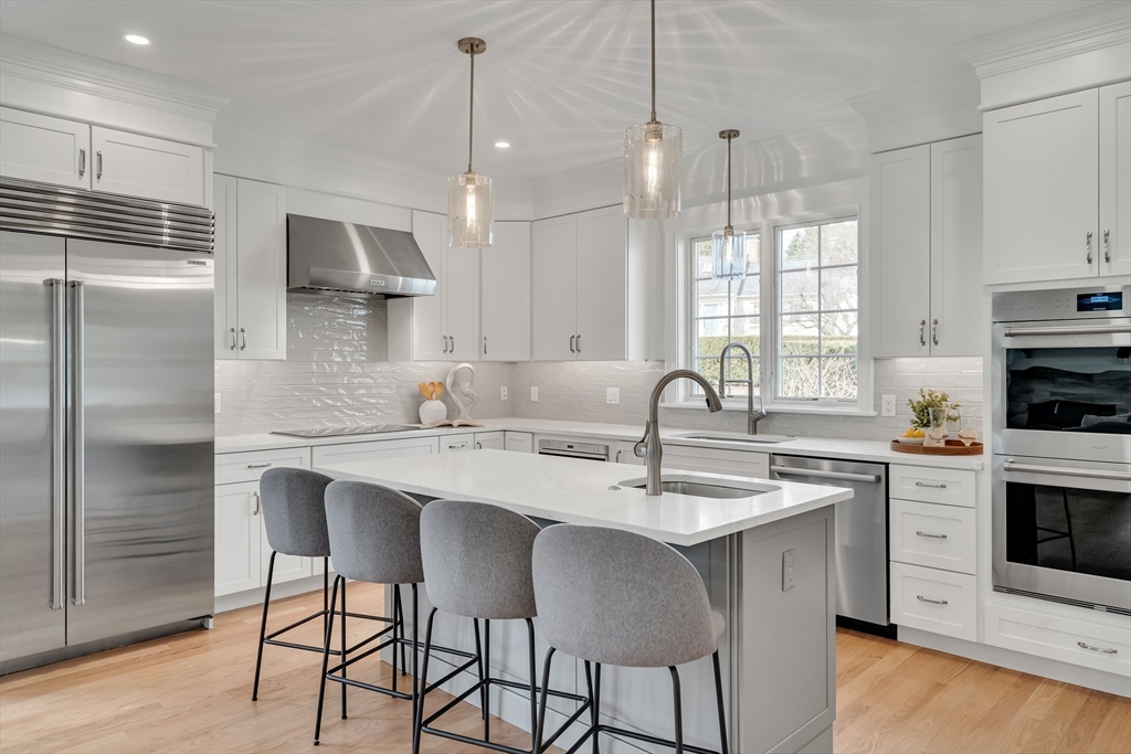 17 Hamilton Road Lexington, MA 02420 - Photo 9 of 42 a kitchen with stainless steel appliances granite countertop a sink a stove a refrigerator and island with wooden floor