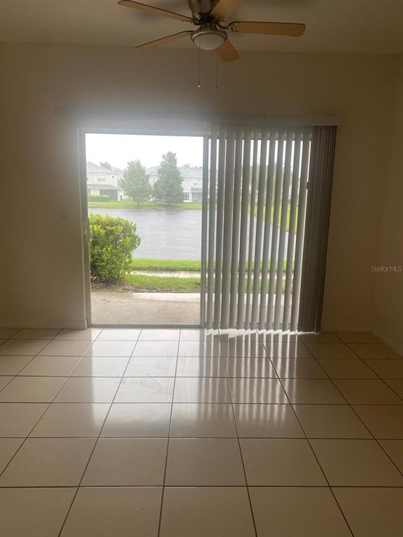 9323 Flowering Cottonwood Road Orlando, FL 32832 - Photo 8 of 23 a view of an empty room with a floor to ceiling window and a ceiling fan