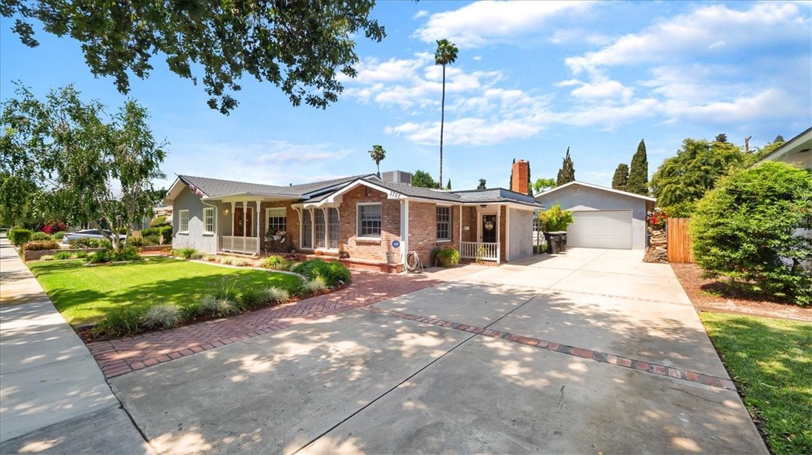 a front view of a house with a garden and trees