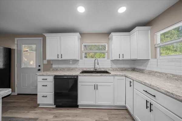 a kitchen with stainless steel appliances granite countertop a sink and cabinets with wooden floor