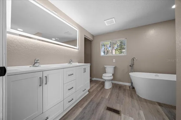 a spacious bathroom with a double vanity sink a toilet and a bathtub