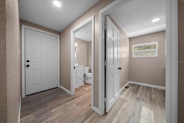 a view of a hallway with wooden floor and a bathroom