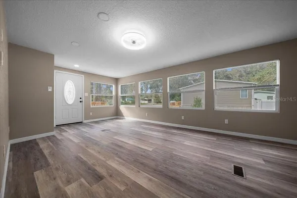 a view of an empty room with a window and wooden floor