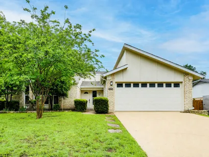 a view of a house with a yard and large tree