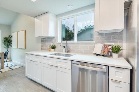 a kitchen with a sink dishwasher and white cabinets
