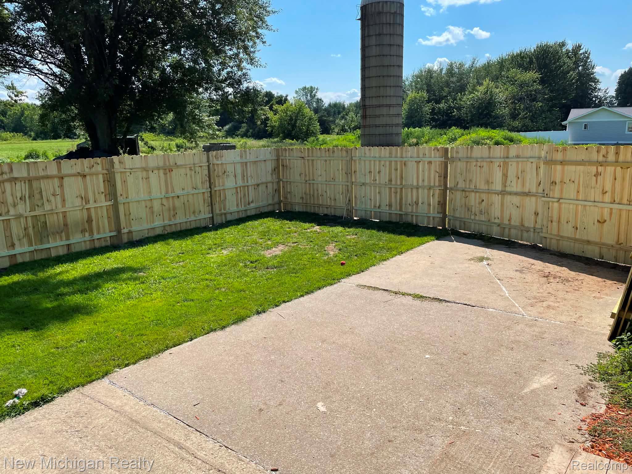 7415 Farrand Road Clio, MI 48420 - Photo 4 of 31 Fenced outdoor area featuring a concrete patio, a section of green lawn, and wood privacy fencing