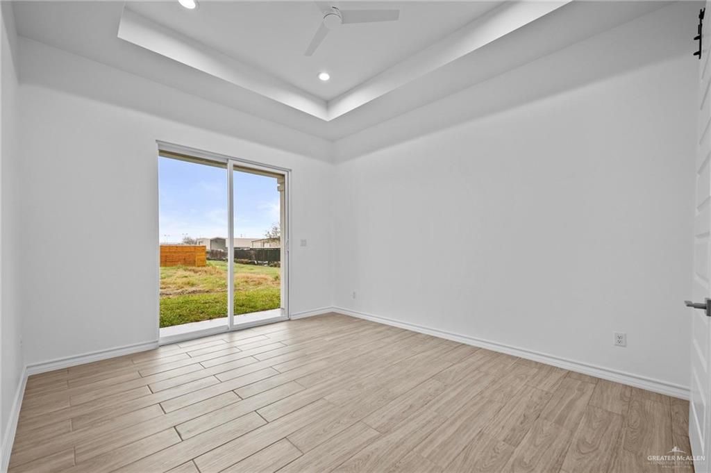 2716 East Conroe Road Edinburg, TX 78542 - Photo 14 of 31 Empty room featuring light wood-style flooring, a tray ceiling, recessed lighting, and a ceiling fan