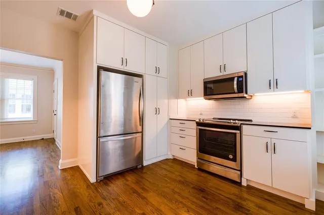 a kitchen with granite countertop wooden floors stainless steel appliances and sink