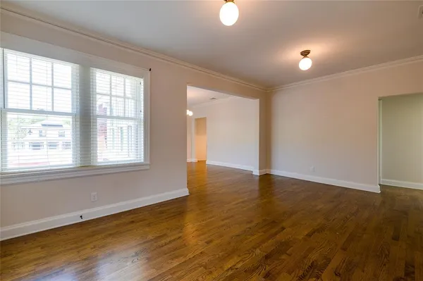 a view of an empty room with wooden floor and a window