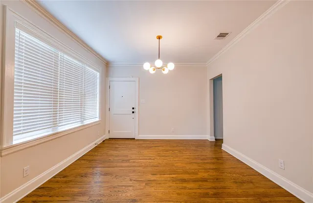a view of an empty room with chandelier fan and wooden floor