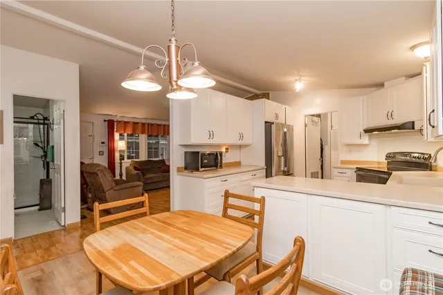 a kitchen with stainless steel appliances kitchen island granite countertop a refrigerator a stove top oven a sink dishwasher and white cabinets