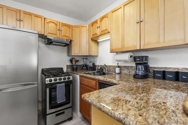 a kitchen with stainless steel appliances granite countertop a stove a sink and a white cabinets