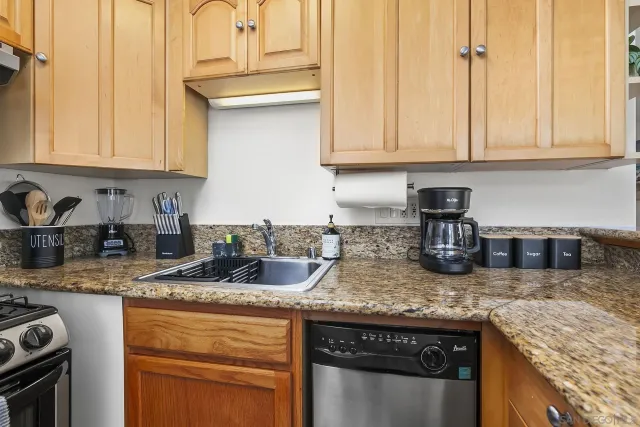 a kitchen with granite countertop a sink a stove and cabinets