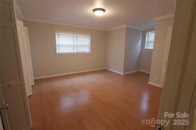 a view of a hallway with wooden floor and a bathroom